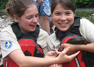 Photo of two female students holding a hellbender salamander.